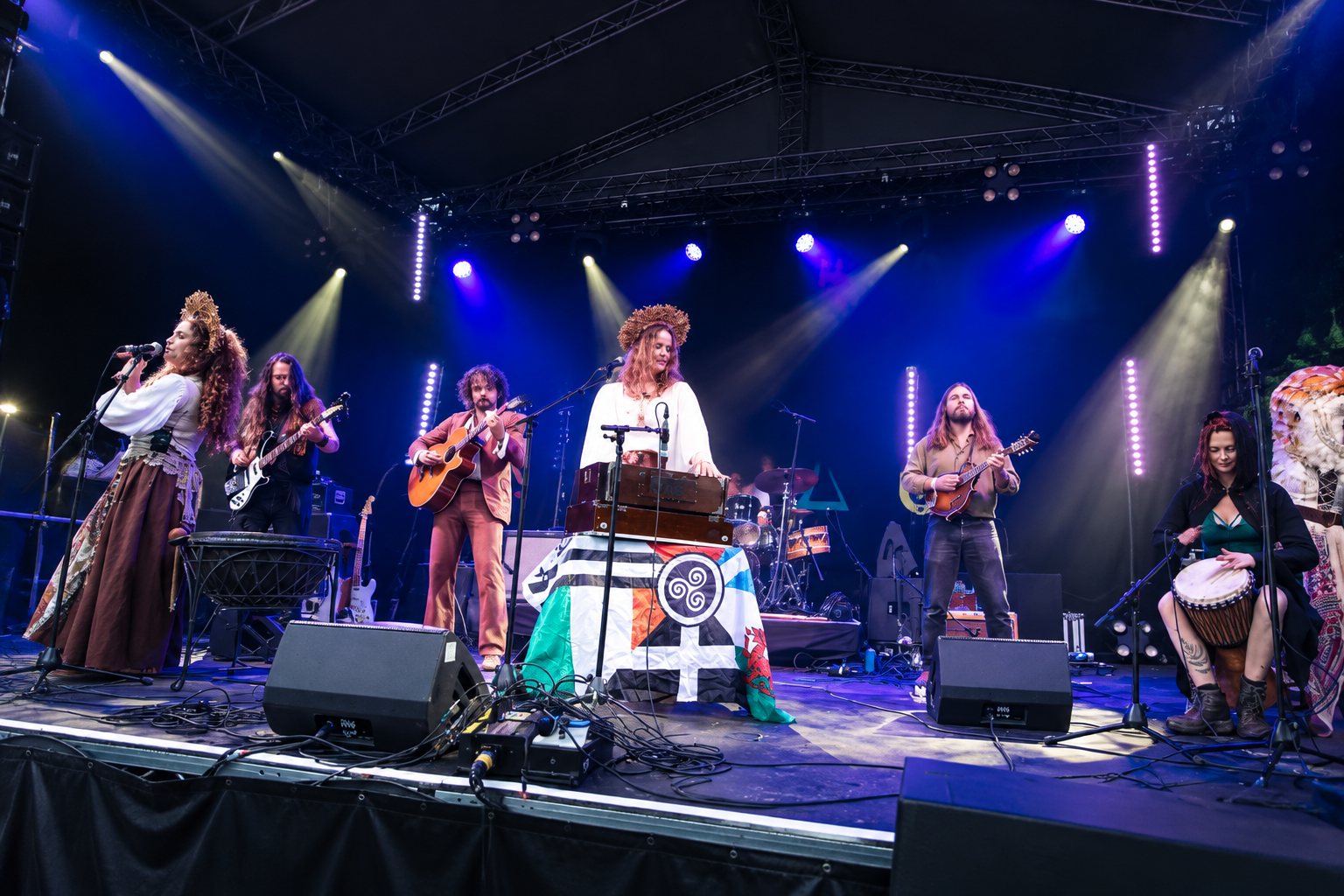 Joe Broughton's Conservatoire Folk Ensemble performing at Green Man, a large group of musicians on a small tent stage